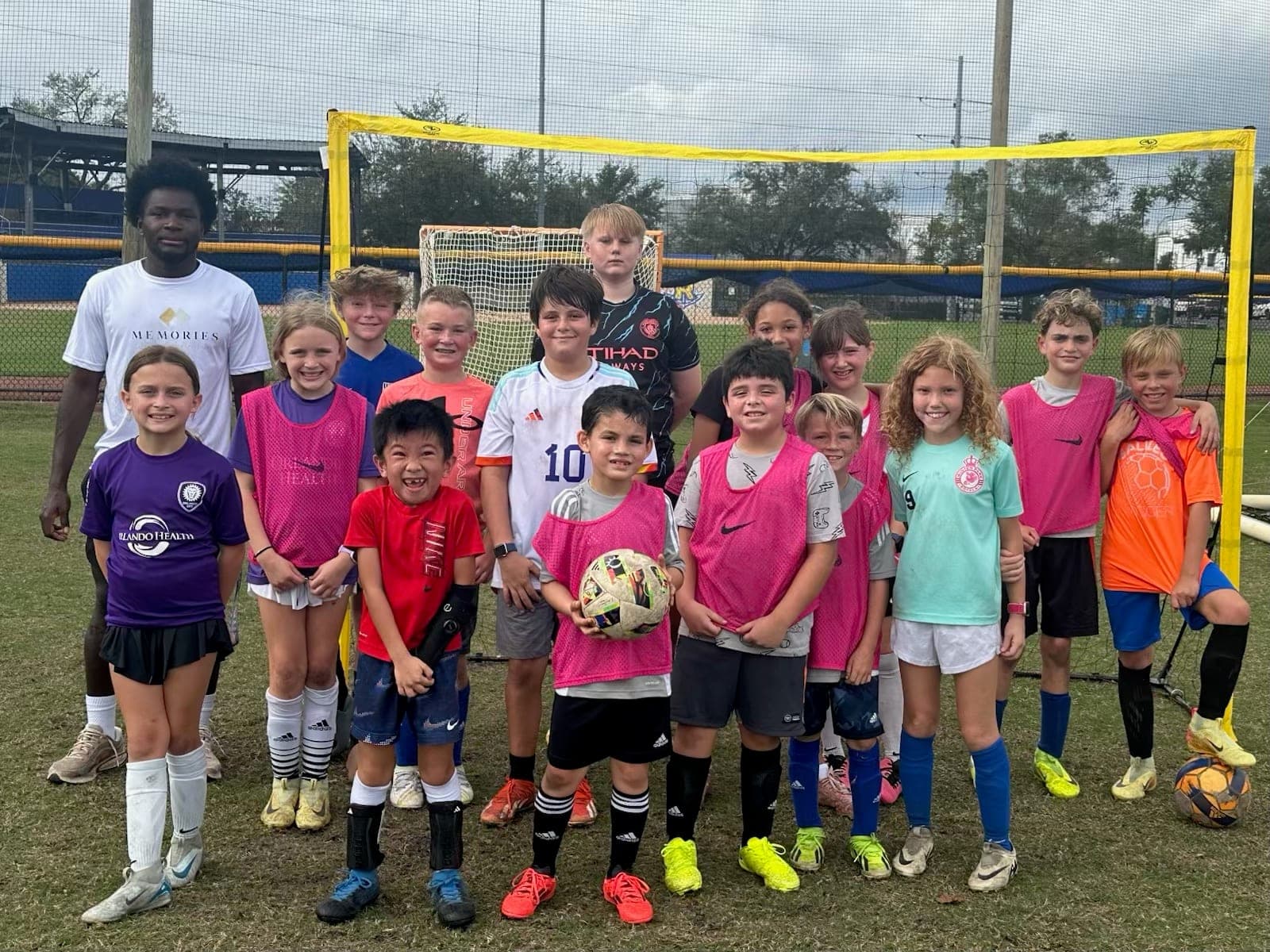 A camp group and their coach in front of the goal at the end of a session.