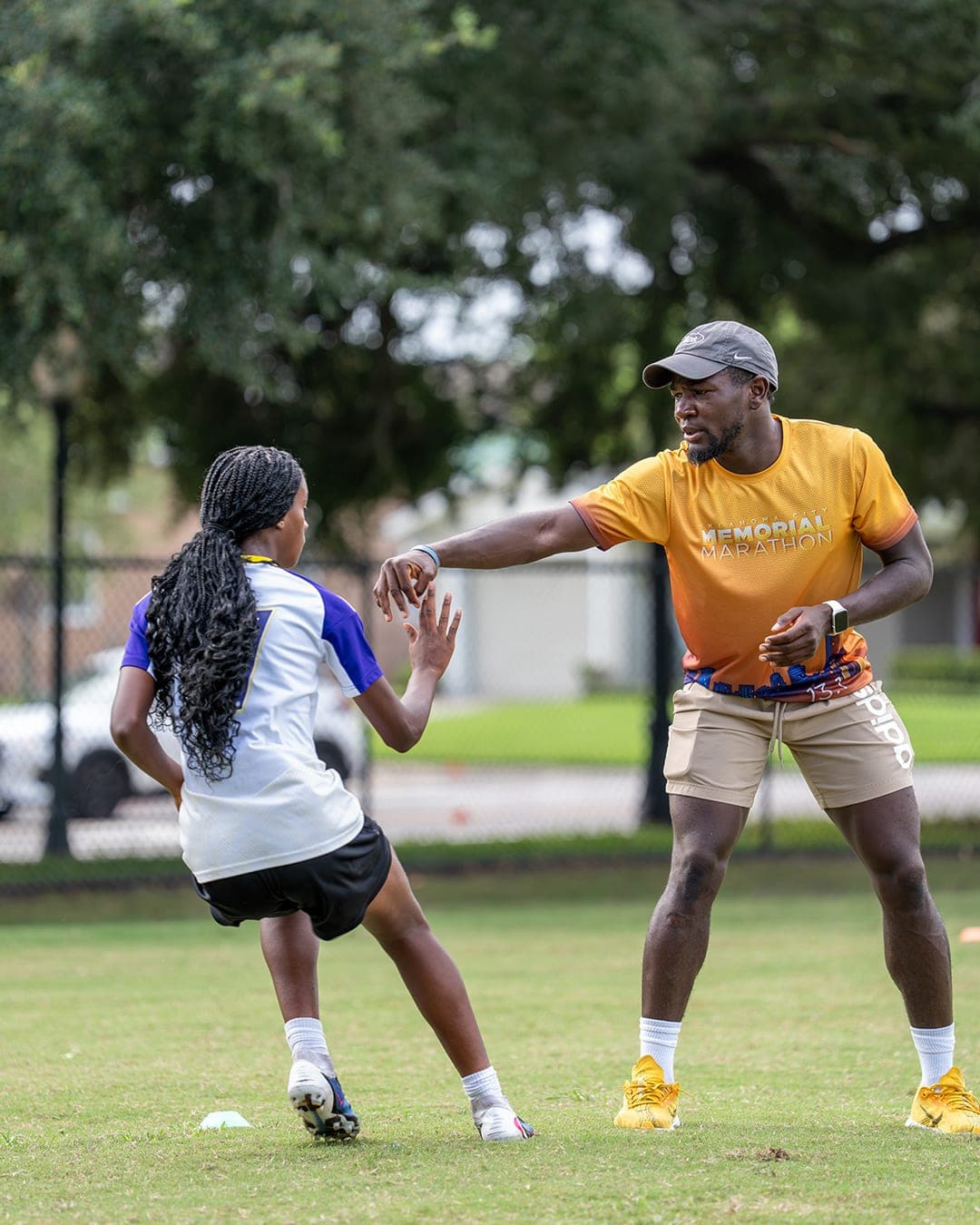 A coach guiding a player through a 1v1 defending exercise on the training field.