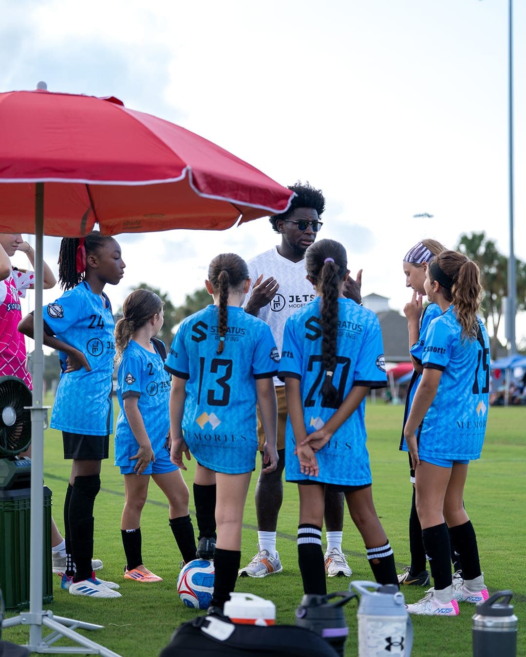 A coach talking through the game plan with the team on the sideline.